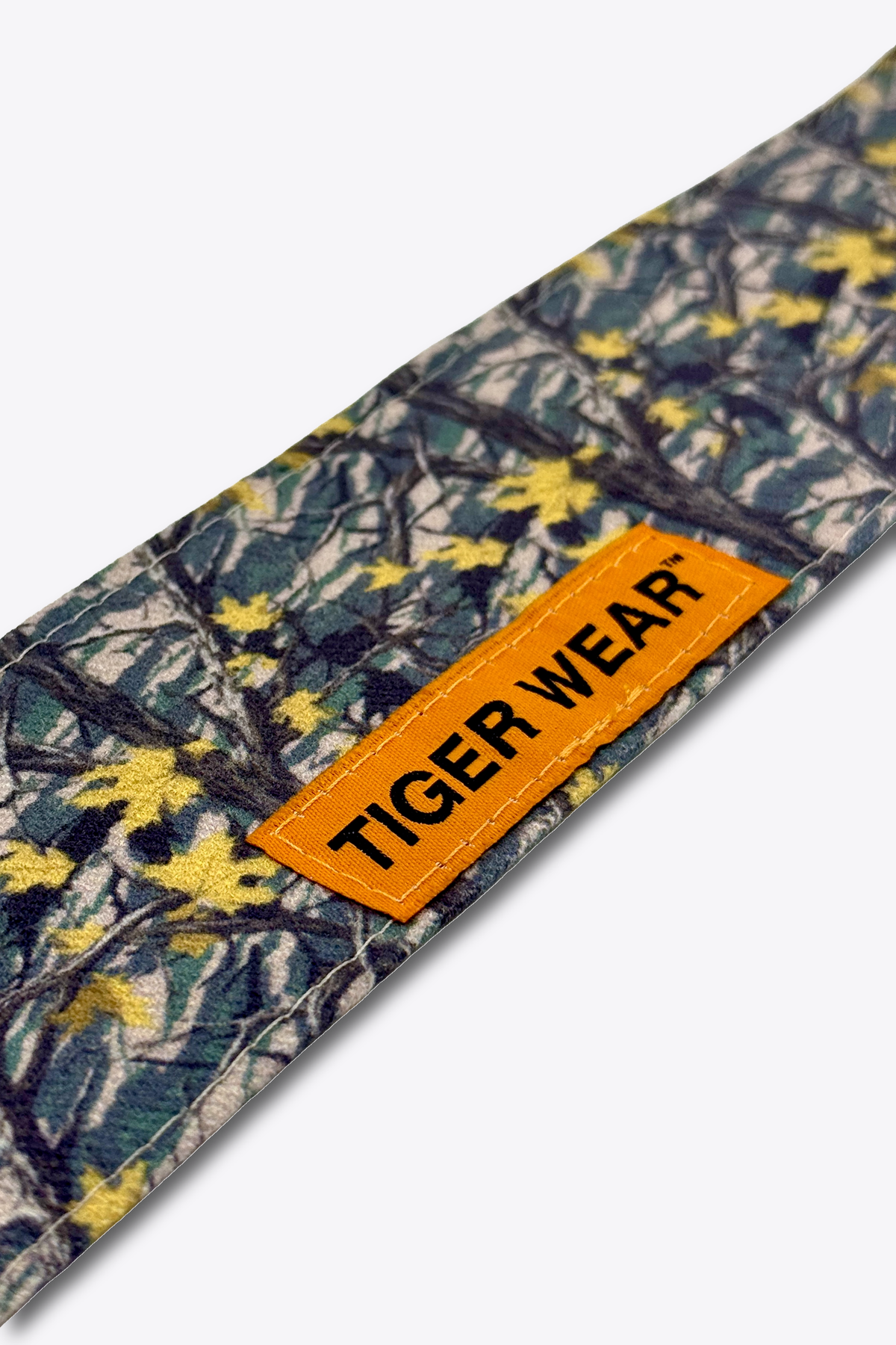 Close up of the orange woven Tiger Wear label on the Late October headband, gray and gold birch leaf camo