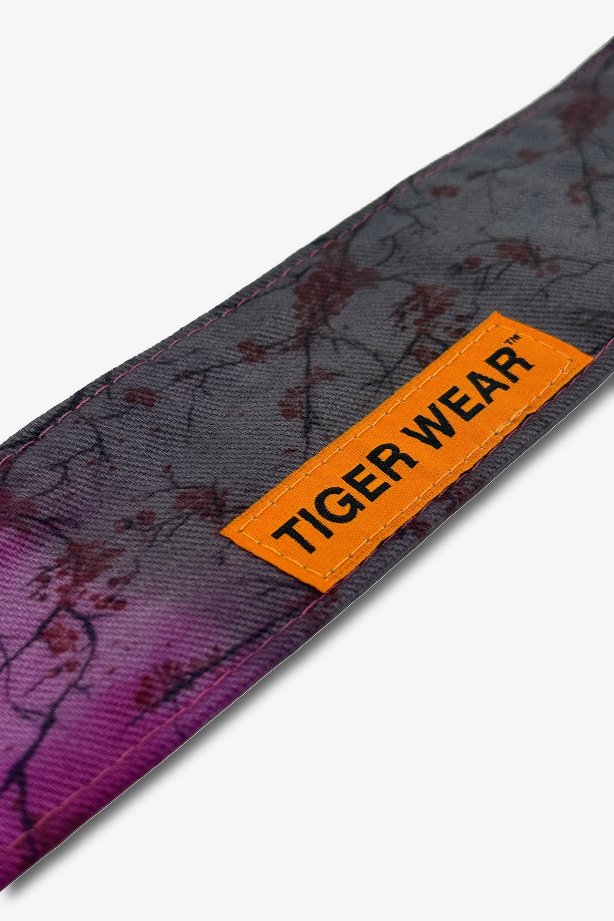 Close up of the orange woven Tiger Wear label on the Bloom at Dusk headband, magenta to charcoal blossom print
