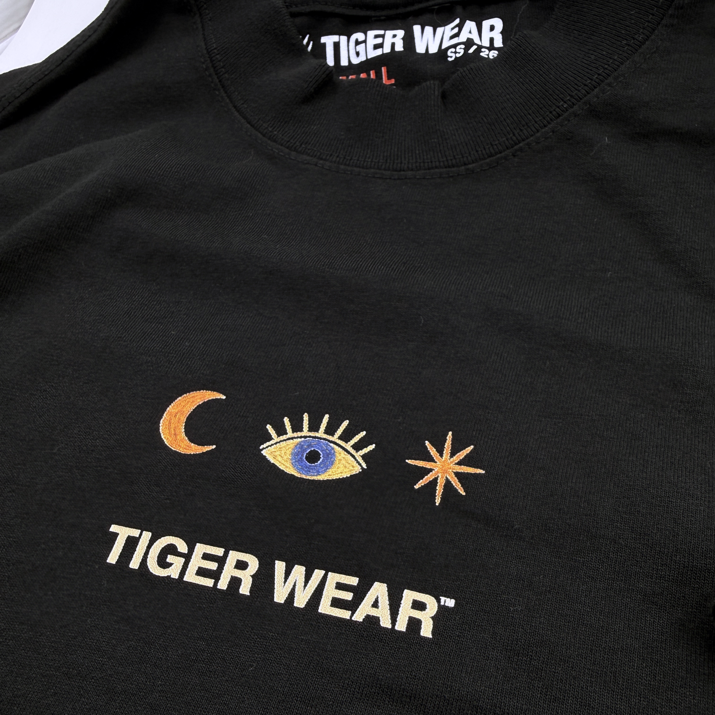 Close up of the chest print and neck label on a black Tiger Wear paintball tee