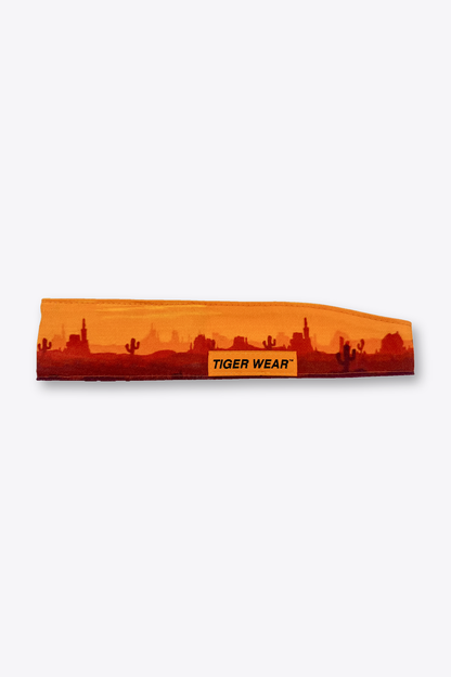 High Noon paintball headband by Tigerwear in orange desert sunset print, laid flat with orange woven label