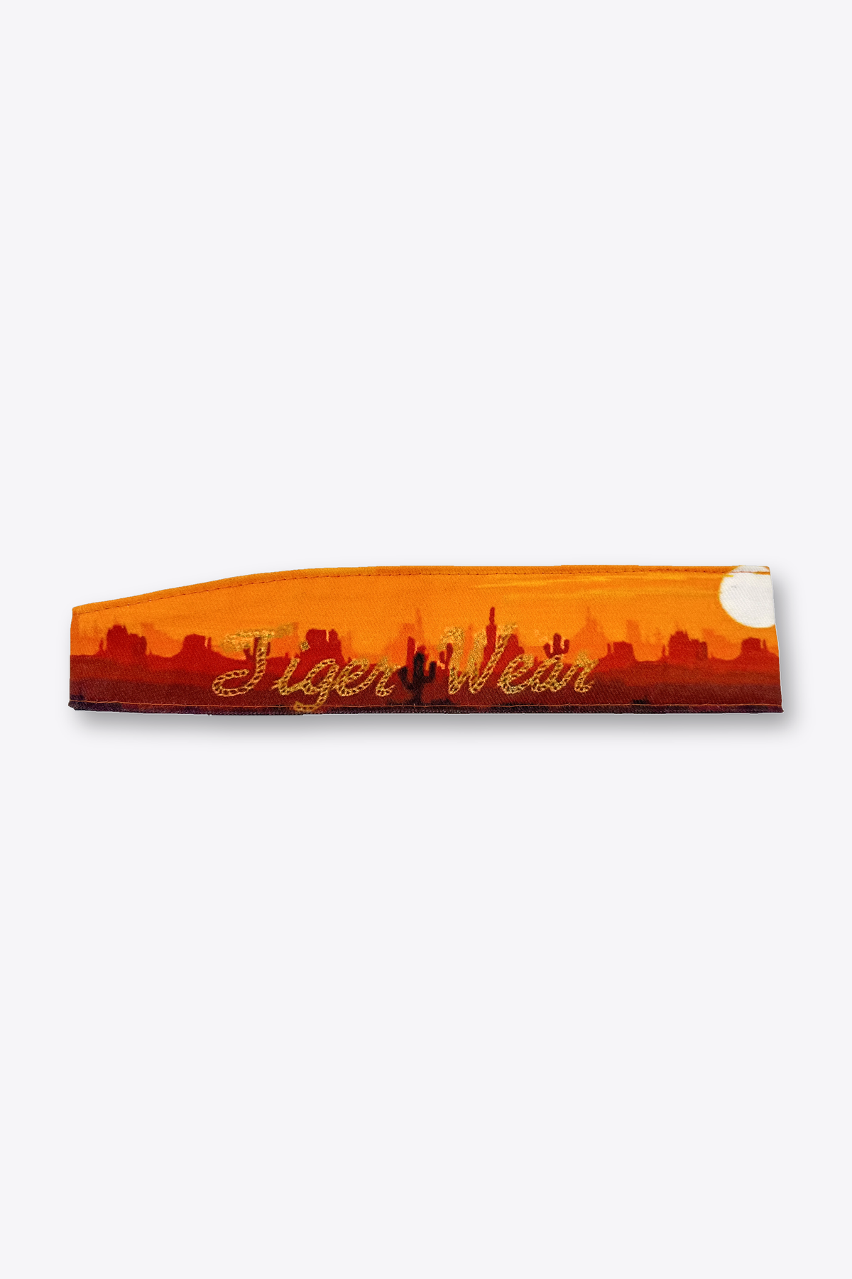 High Noon paintball headband by Tigerwear, laid flat showing the gold rope script over the orange desert sunset print
