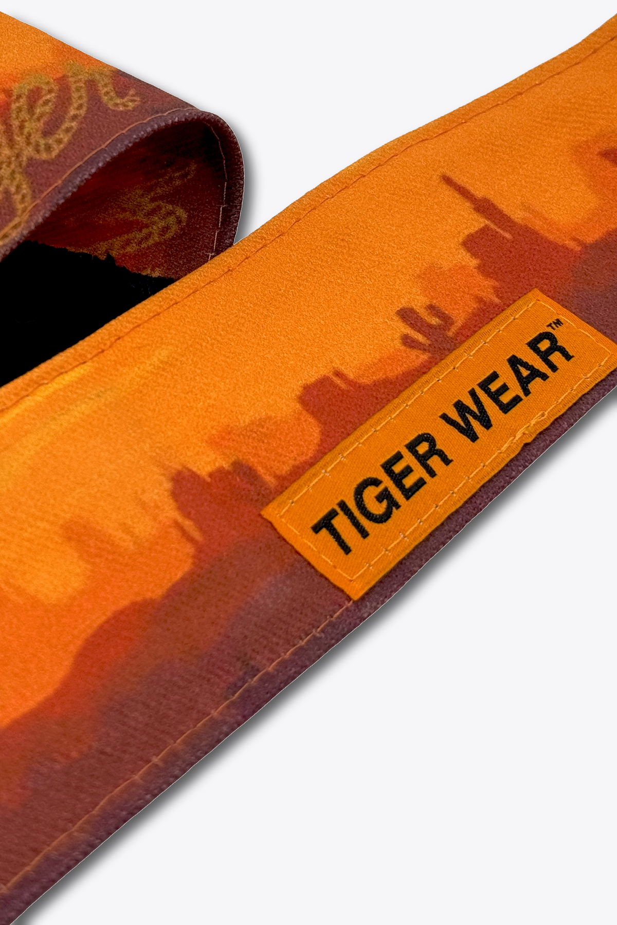 Close up of the orange woven Tiger Wear label on the High Noon headband, orange desert sunset print