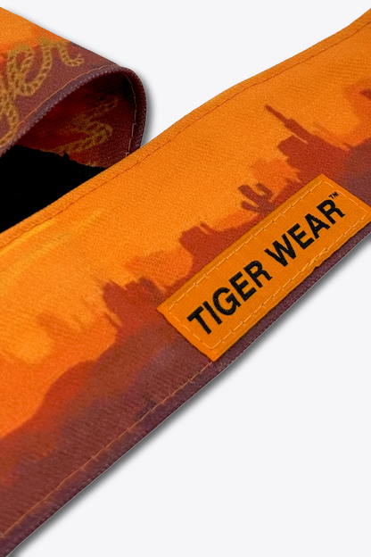 Close up of the orange woven Tiger Wear label on the High Noon headband, orange desert sunset print